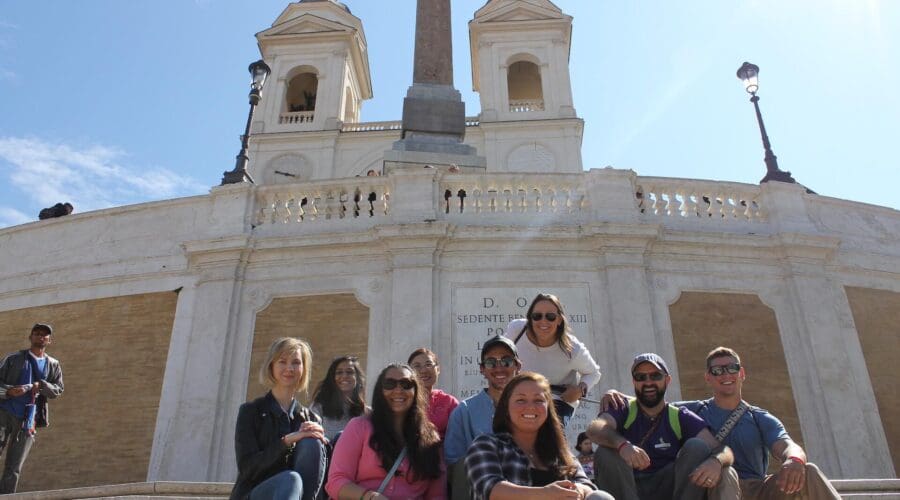 A group of people smiling and sitting on the Spanish steps in Rome