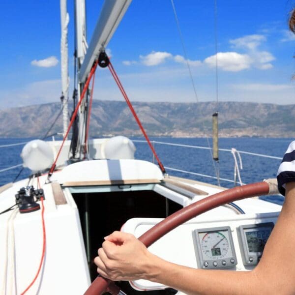 Woman standing at the steer of a sailboat