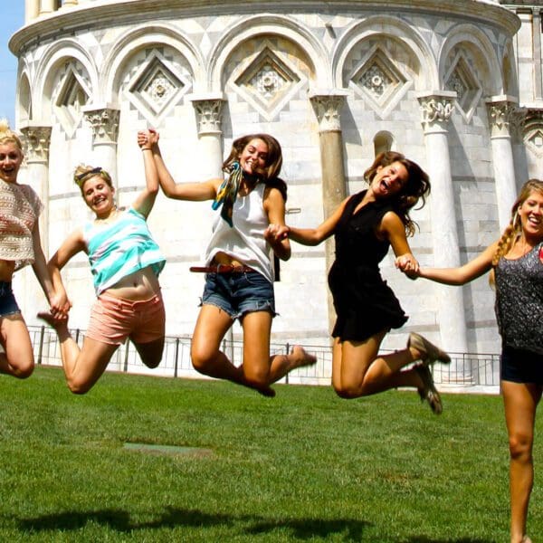 Group of friends jumping in front of the Leaning Tower of Pisa