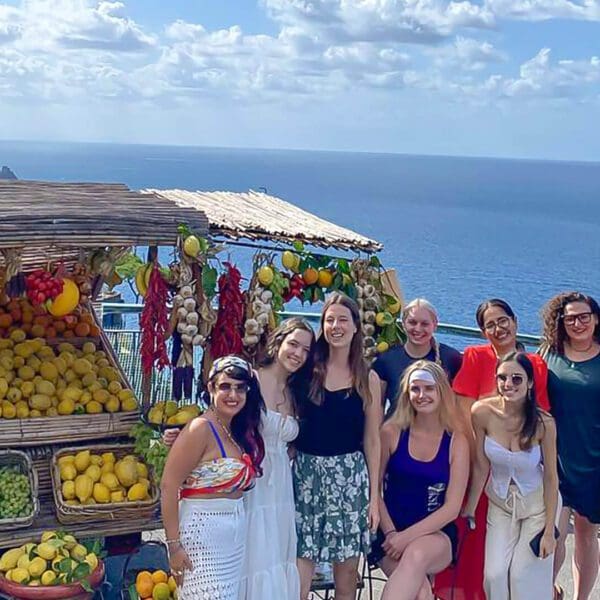 Group of friends standing in front of a fruit stand in the Amalfi Coast