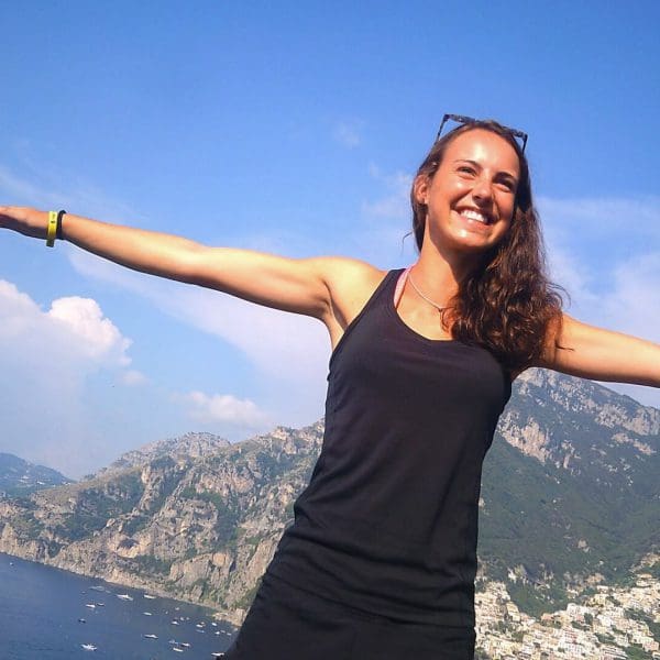 A woman spreading her arms and smiling in Positano